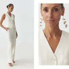 Elegancka stylizacja: jak nosić kamizelkę damską w białym total looku. Modelka prezentuje białą kamizelkę i spodnie, uzupełnione złotą biżuterią.