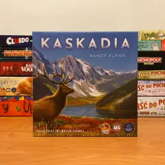 Gra planszowa Kaskadia z jeleniem na okładce, otoczona innymi grami jak Cluedo, Pandemic, Monopoly.