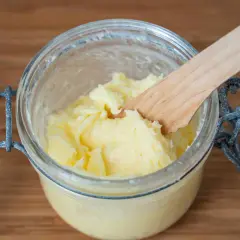 Frisch gemachte Butter in einem Glas, mit einem Holzspatel. So einfach kann man Butter selber machen!