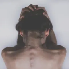 Vista posteriore di una persona con le mani tra i capelli, che evoca un senso di disagio legato alla rupofobia e alla sessualità.