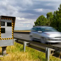 Un appareil de contrôle homologué en mouvement, un radar de vitesse sur le bord de la route, observe une voiture passer à toute allure.