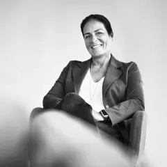 Manuela Reibold-Rolinger lächelt freundlich in die Kamera, während sie in einem Sessel sitzt. Sie trägt einen Blazer und Jeans.