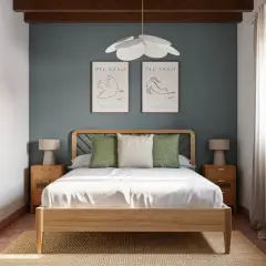 Lámpara de techo de madera sobre una cama con cabecero de diseño. Dos cuadros de Picasso decoran la pared azul.