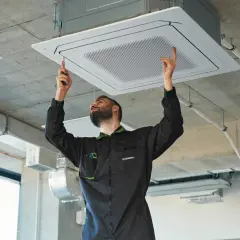 Técnico instalando equipos de climatización en el techo.