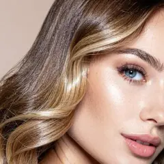 Mujer con cabello castaño y rubio, con un "money piece" que ilumina su rostro. Sus ojos azules y labios rosados resaltan su belleza.