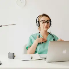 Lekarka w słuchawkach z mikrofonem wyjaśnia pacjentowi przez internet, jak stosować antybiotyk 3 dniowy.