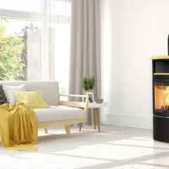 Moderner Kaminofen in Gelb und Schwarz mit brennendem Holz. Der Ofenrohr Abstand zum Holz ist sicher eingehalten.