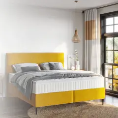 Ein gelbes Boxspringbett mit einer Matratze, die für erholsamen Schlaf sorgt.