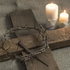 Korona cierniowa, krzyż i gwoździe na płótnie. Płonące świece symbolizują refleksję nad tym, ile trwa nabożeństwo wielkopiątkowe.