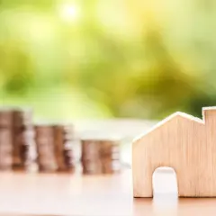 Une petite maison en bois et des piles de pièces de monnaie suggèrent un coup de pouce pour quel groupe : les investisseurs immobiliers.