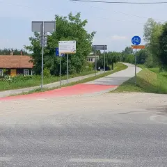 Czerwony pas wyznacza nowe trasy rowerowe w Tarnowie. W tle domki i zielone drzewa.