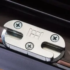 Metalowe okucie okna z logo producenta, przykręcone do ramy okiennej.
