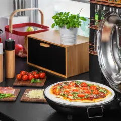 Gotowa pizza na kamieniu w otwartym piecyku, obok składniki: pomidorki, rukola, szynka, ser.