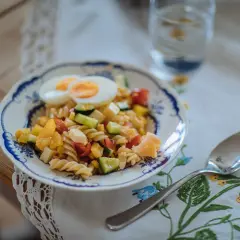 En skål med vegetarisk pastasallad med ägg, grönsaker och ost. En proteinrik och färgstark måltid.