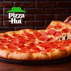 Pizza pepperoni z ciągnącym się serem, podnoszona przez rękę. Logo Beyond Meat i Pizza Hut w tle.