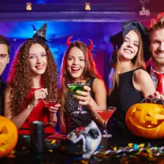 Glada vänner firar halloween med drinkar och pumpor. Perfekt för halloween lekar vuxna!