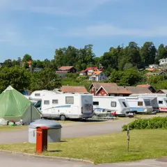 Husvagnar och husbilar står uppradade på en campingplats i Norrköping. En grön kupoltält står i förgrunden.
