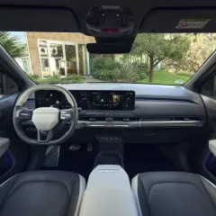 Interior del Kia EV3 con pantalla táctil panorámica, volante moderno y asientos de dos tonos.