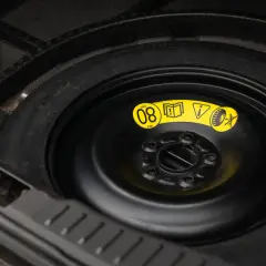 Koło dojazdowe w bagażniku. Na żółtej naklejce widać symbol informujący, ile można jechać na kole dojazdowym: MAX 80 km/h.