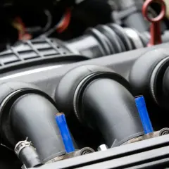 Detalle del colector de admisión de un coche, con tubos negros y pequeños detalles azules.