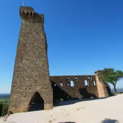 Ruinen der Burg von Châteauneuf-du-Pape, ein imposanter Turm und zerfallene Mauern unter blauem Himmel.