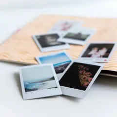 Zdjęcie 10x15 to format, który idealnie pasuje do albumu. Kilka polaroidów leży na ozdobnej karcie.