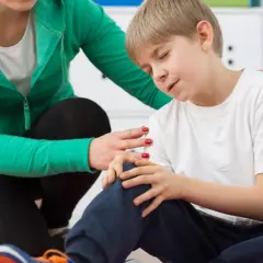 Fizjoterapeuta pociesza chłopca z bólem kolana.