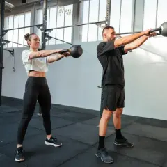 Para, co to jest crossfit, wykonuje ćwiczenie z kettlebell. Intensywny trening buduje siłę i wytrzymałość.