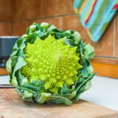 Zielony brokuł romanesco o spiralnym kształcie, gotowy do przygotowania na desce do krojenia w kuchni.