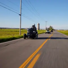 Trzykołowe motocykle jadące w kolumnie po wiejskiej drodze. Zjawisko shimmy może wystąpić przy większych prędkościach.