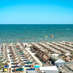 Słoneczne rumuńskie wakacje nad Morzem Czarnym. Plaża pełna leżaków i parasoli, ludzie kąpią się i relaksują.