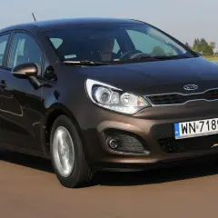 Brązowe Kia Rio 3 w ruchu drogowym, z widocznym kierowcą i tablicą rejestracyjną WN-7189C.