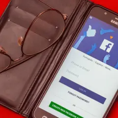 Okulary leżą na etui z telefonem wyświetlającym ekran logowania Facebooka.
