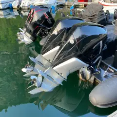 Motori fuoribordo Mercury Verado, con eliche lucide che riflettono l'acqua verde. L'alto bordo del gommone è visibile, pronto per la navigazione.
