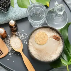 Ingredientes para el agua de arroz para el pelo: arroz, aceites, peine de madera, cepillo y toalla.