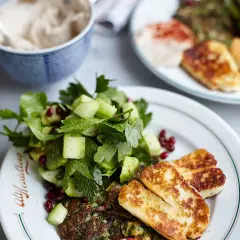 En härlig tallrik med stekt halloumi, en fräsch sallad med gurka och granatäpple, samt en grön röra. Ett perfekt halloumi recept för en lätt måltid.