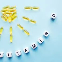 Żółte kapsułki i kostki z literami tworzą napis "WITAMINA D". To najlepsza witamina D3 lek na zdrowie.