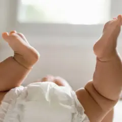 Gambe paffute di un neonato con pannolino, un tenero culo rosso pronto per un cambio.