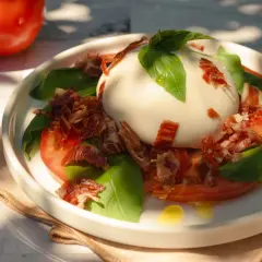 Deliciosa ensalada de burrata con tomates, albahaca fresca y crujiente jamón serrano.