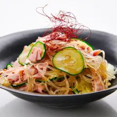 A refreshing harusame salad with glass noodles, sliced cucumber, and ham, garnished with delicate red chili threads.