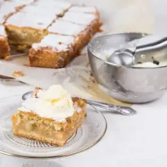 Pyszna szarlotka z kawałkami jabłek, posypana cukrem pudrem, podana z lodami. Idealne jabłka do szarlotki to podstawa!