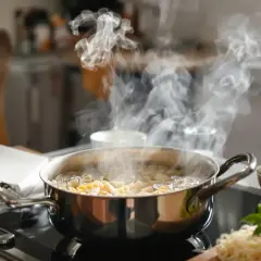 Para podgrzać makaron z sosem, gotuj go w garnku na kuchence indukcyjnej. Para unosi się nad gotującym się makaronem.