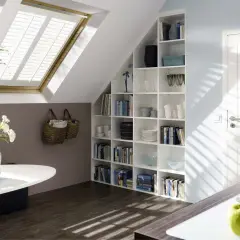 Una libreria in mansarda, piena di libri e oggetti decorativi, si integra perfettamente con l'ambiente.