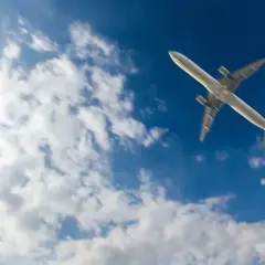 Samolot leci na tle błękitnego nieba z chmurami. Wkrótce lądowanie w Marsa Alam.