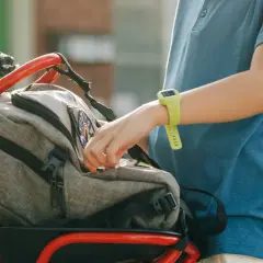 Kind packt seinen schulranzen auf dem Fahrrad. Ein silberner Trinkflaschenhalter ist ebenfalls am Fahrrad befestigt.