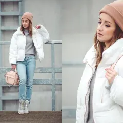 Dziewczyna w beżowej czapce i puchowej, biała kurtka wiosenna, dżinsy i różowa torebka.
