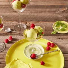 Erfrischendes Kiwi-Sorbet mit Himbeeren und Minze in eleganten Gläsern auf Holzhintergrund.