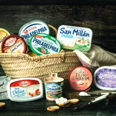 Variedad de quesos crema en cestas y recipientes, incluyendo marcas como Philadelphia y Président. Ideal para untar y disfrutar.