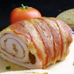 Roladki z indyka z boczkiem, soczyste i aromatyczne, gotowe do podania z pomidorem i chlebem.