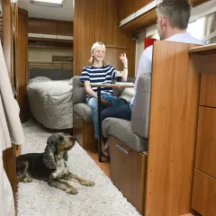 Un enfant et un homme discutent dans un camping-car, un chien au sol. Une astuce chauffage camping-car pour un voyage confortable.